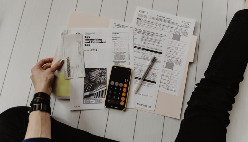 Tax documents, calculator, and financial statements spread across a desk
